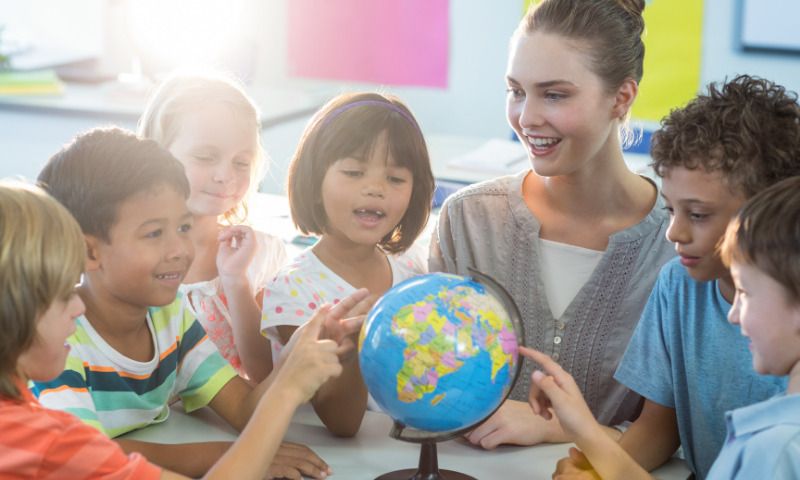 Benachteiligung Coronajahrgang: Gefährdet Homeschooling Zukunft des Kindes? Lehrerin mit Schülern und Globus