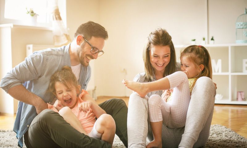 Corona-Stress und Entspannung: Eltern haben im Wohnzimmer Spaß mit ihren zwei Töchtern