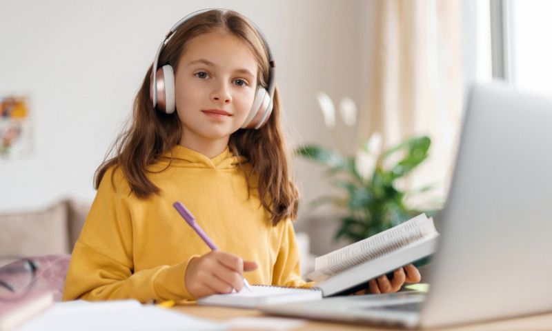 Ferienkurs: Mädchen lernt mit Laptop und Kopfhörern