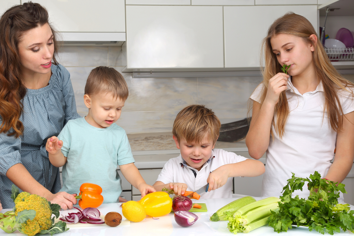 Gemüse für Kinder: Mutter und Kinder schneiden gemeinsam Gemüse