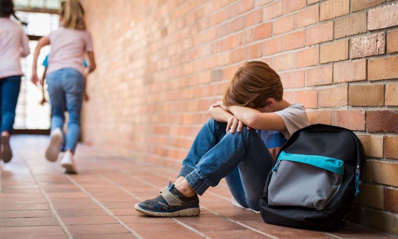 Selbstbewusstsein bei Kindern staerken: Junge traurig und einsam in der Schule