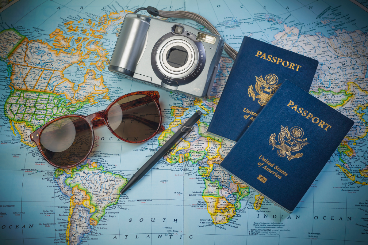 Sommrferien Urlaub: Weltkarte mit Reisepäsen, Kamera, Sonnenbrille und Stift