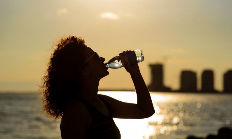 Draußen lernen: Frau trinkt Wasser bei Sonnenschein