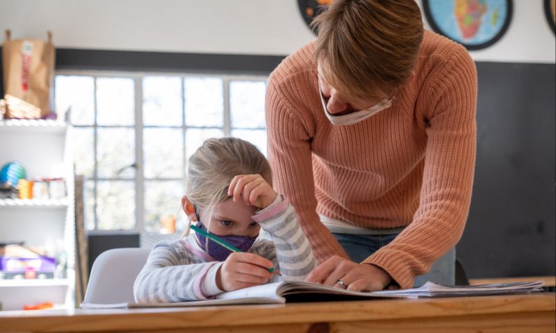 Hygienekonzepte an Schulen: Mädchen bekommt Hilfe bei den Hausaufgaben