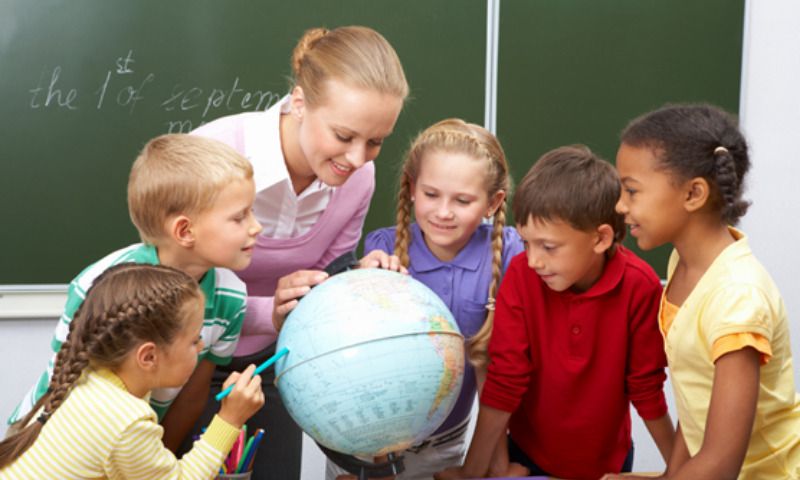 Lernerfolg: Lehrerin zeigt Schülern einen Globus