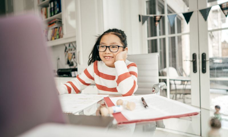 Medienkompetenz: Kind erledigt froehlich Hausaufgaben mit dem Laptop