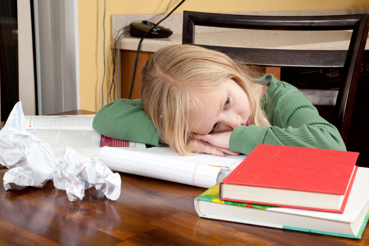 Kind will keine Hausaufgaben machen_Schulmädchen sitzt unmotiviert am Schreibtisch