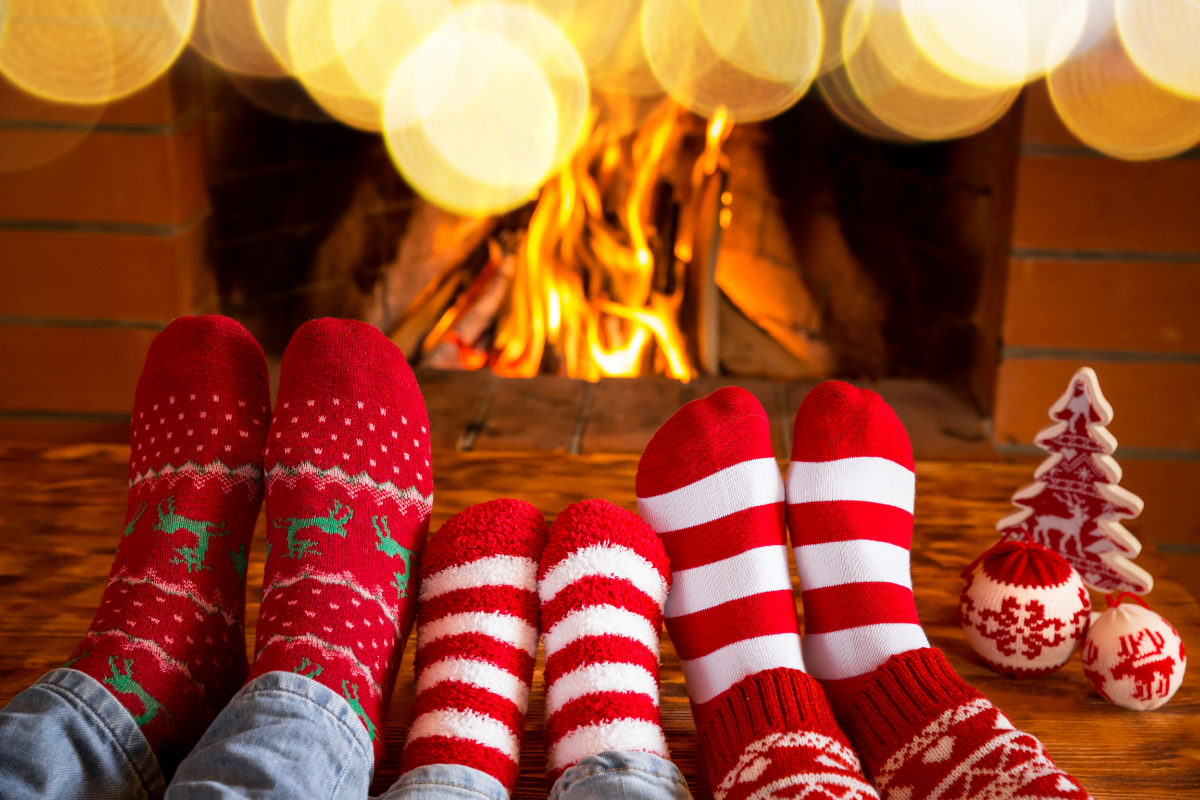 Vorweihnachtszeit Familien-Aktivitäten_Familie sitzt mit roten Socken vor Kamin