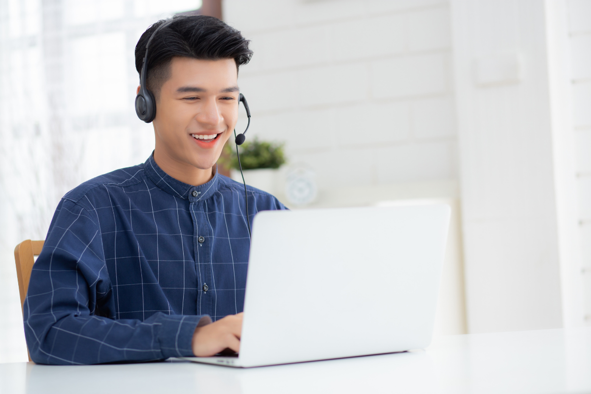 Deutsch lernen für Anfänger, Junge sitzt vor dem Laptop mit Kopfhörern