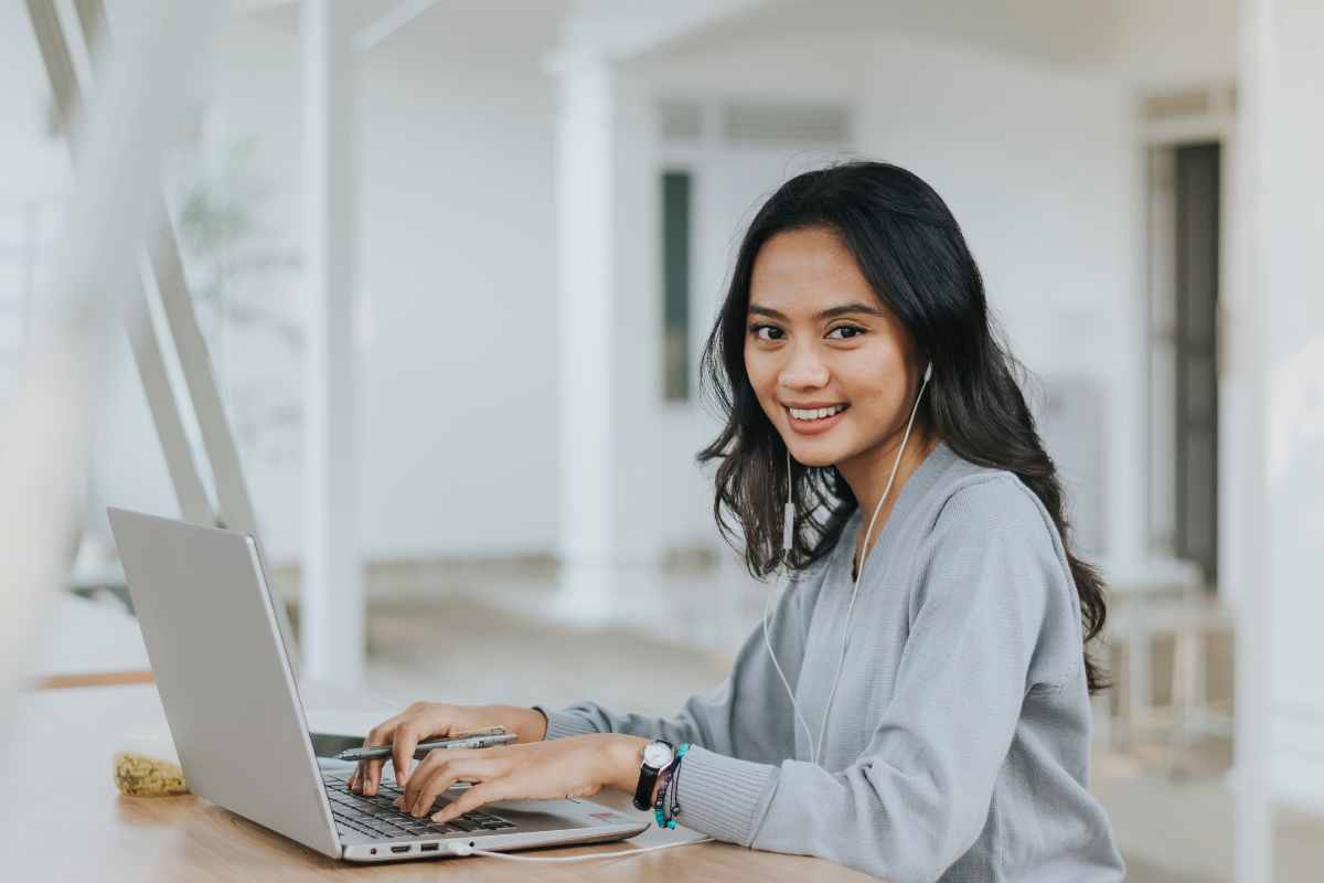 Business Englisch, Frau sitzt am Laptop mit Kopfhörern