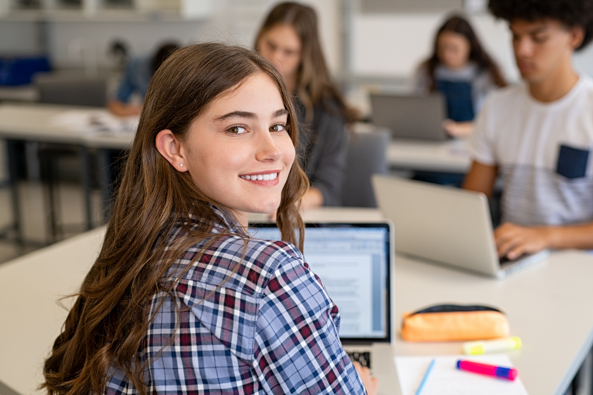 Schulwechsel Realschule Gymnasium, Mädchen lächelt glücklich über die Schulter