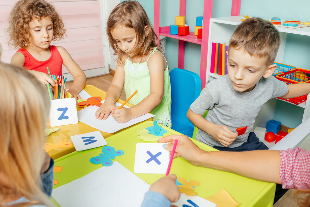 Sprachförderung in der Kita, Kinder sitzen am Tisch Buchstabenkarten
