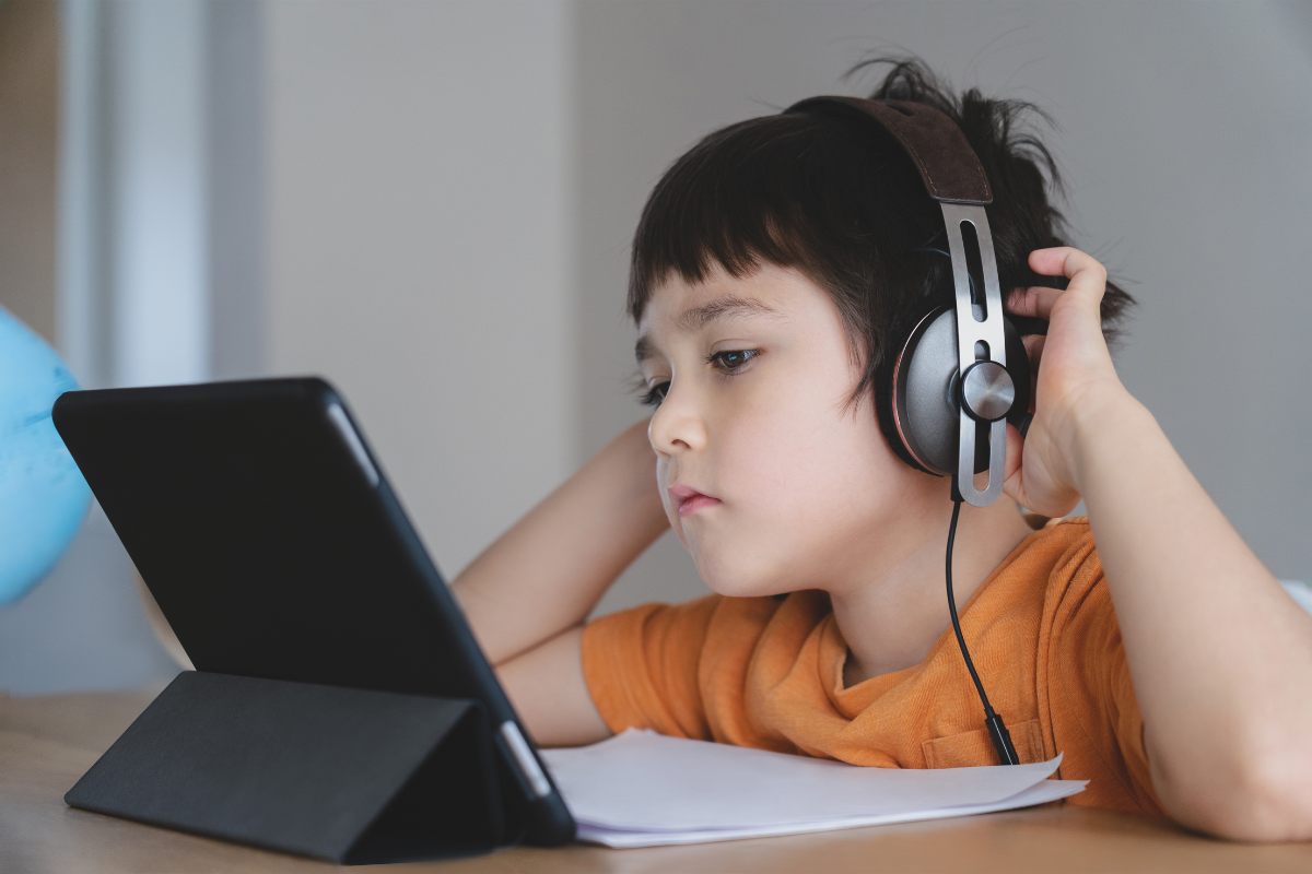 Jahreszeugnis-Aktion, Kind sitzt mit Kopfhörern vor einem Tablet