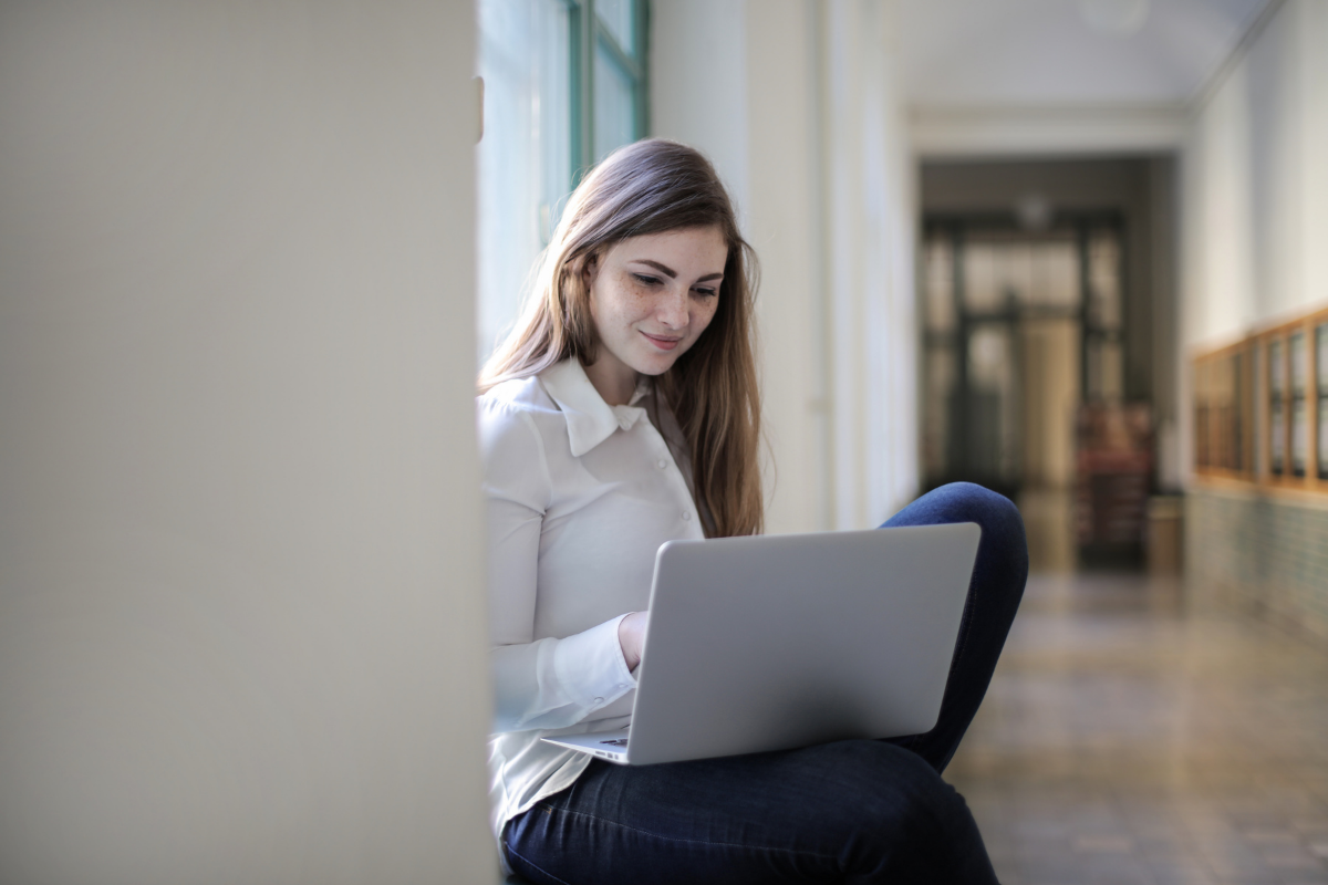 Corona-Abitur, Schülerin sitzt mit Laptop im Gang einer Schule