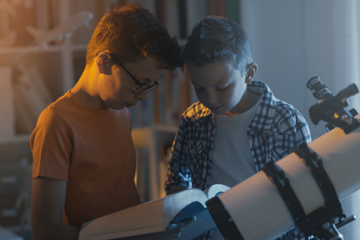 Hochbegabung bei Kindern, zwei Jungen mit Buch und Teleskop