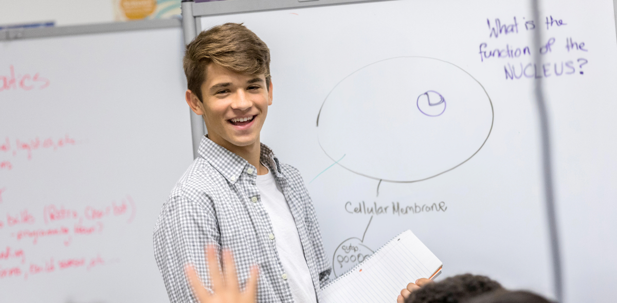 mündliches Abitur- Schüler steht vor Tafel in Klassenzimmer_