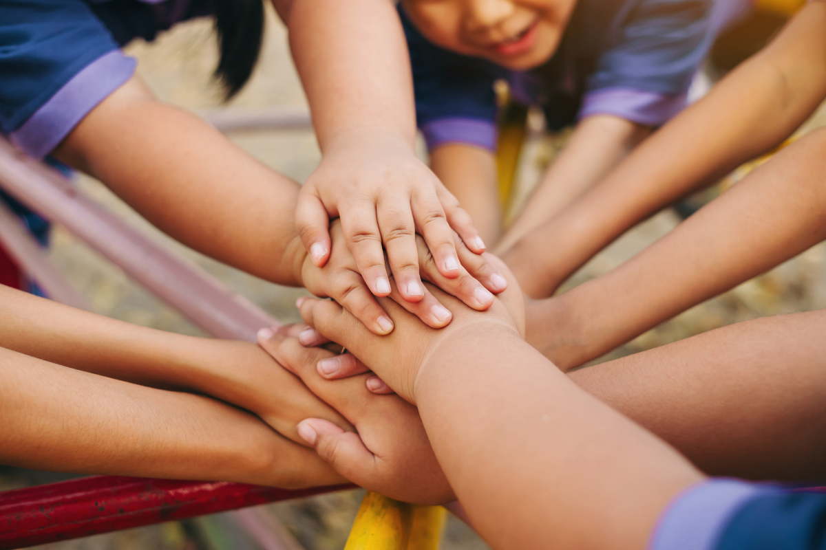 Inklusionsschule, Kinder halten ihre Hände in die Mitte