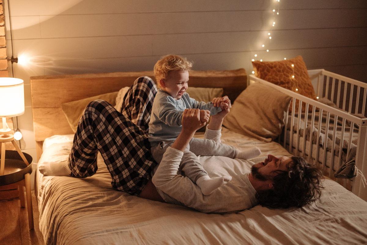 Kind alleine einschlafen, Vater und Kind spielen im Bett