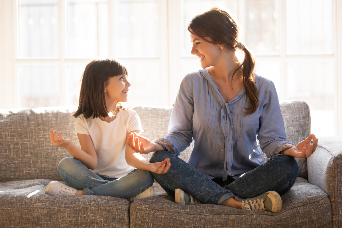 achtsamkeit fuer kinder, mutter und tochter im schneidersitz auf dem sofa