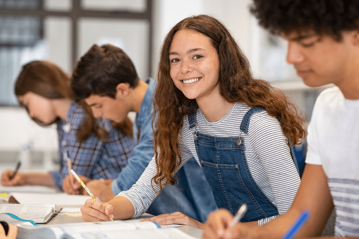 Flüchtigkeitsfehler vermeiden_Schülerin schreibt Klassenarbeit und lächelt