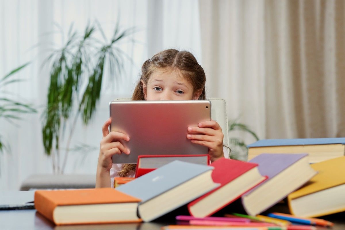 Wortarten bestimmen, Mädchen mit Tablet vor Bücherstapel