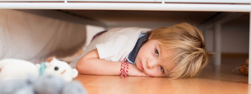 Aengste bei Kindern: Kind liegt unter Bett