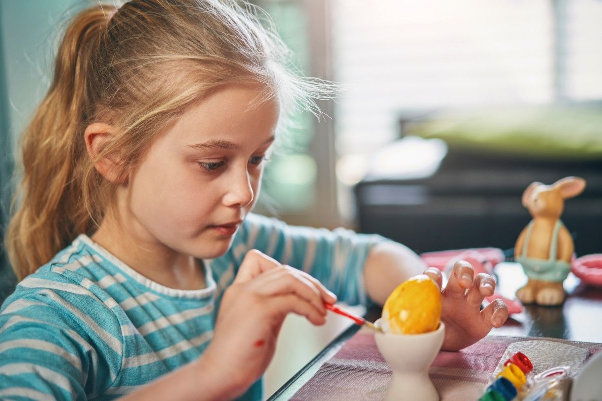 Ostern mit Kindern: Maedchen bemalt Osterei