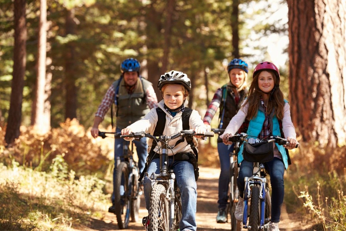 Fahrrad fahren lernen: Familie mit Raedern und Sturzhelmen