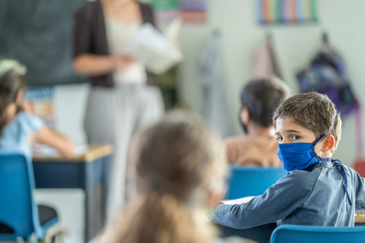 Maskenpflicht in der Grundschule_Junge mit Maske sitzt im Klassenzimmer