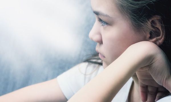 Corona-Aufholprogramm: Mädchen schaut traurig aus Fensterschreibe