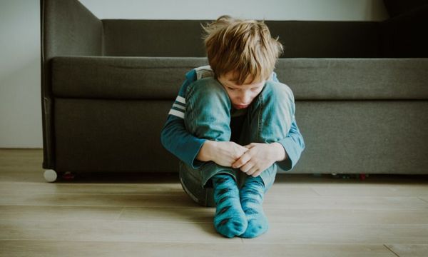 Pandemie gefährdet Gesundheit von Kindern: Junge sitzt allein auf dem Fußboden