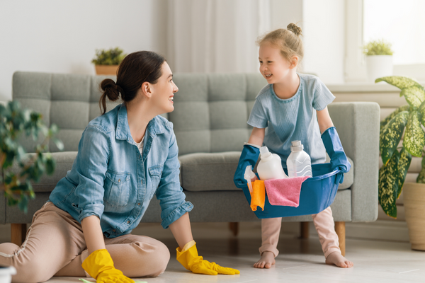 Neujahrsputz mit der Familie_Mutter und Tochter tragen Gummihandschuhe und putzen Wohnzimmer