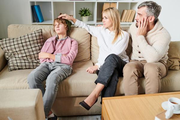 Tipps gegen Liebeskummer_Eltern mit traurigem Sohn auf Couch