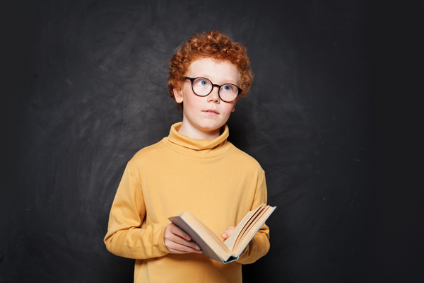 Auswendig lernen_Junge mit kluger Brille und Buch in der Hand