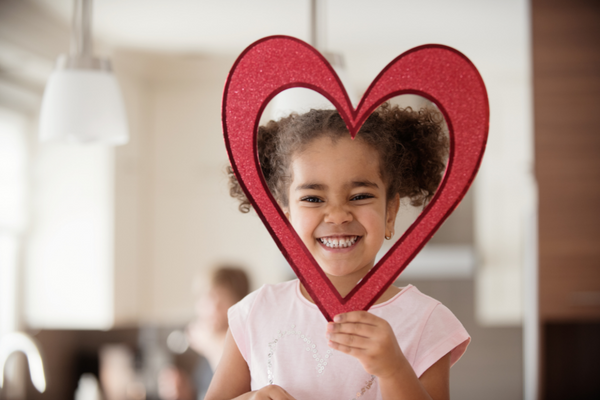 Valentinstag-Geschenk für Kinder_Mädchen hält selbst gebasteltes Herz vors Gesicht