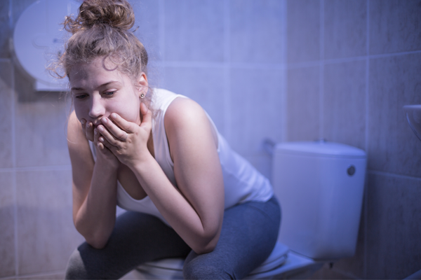 Essstörungen_Mädchen sitzt traurig auf Toilettensitz