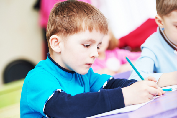 Konzentration fördern Kinder, Junge schreibt konzentriert