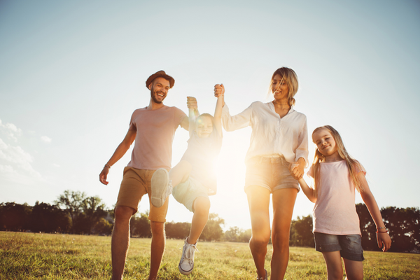 Familienurlaub in Deutschland_Familie hält sich an Händen und läuft über Wiese