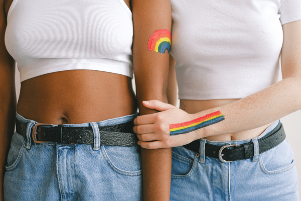 coming out, zwei frauen mit lgbtq flagge auf dem arm