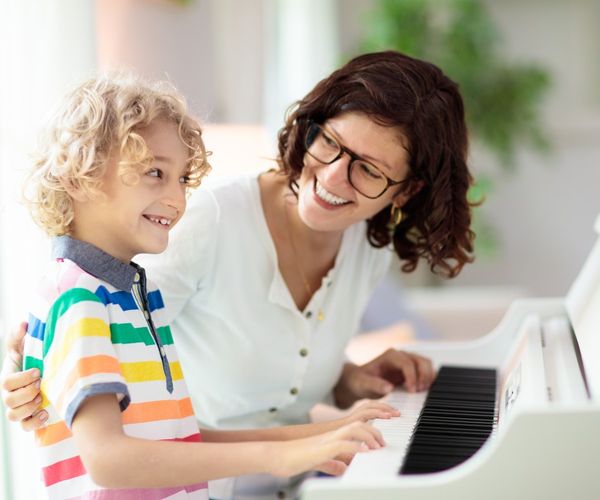 Instrument lernen_Junge sitzt mit Mama am Klavier