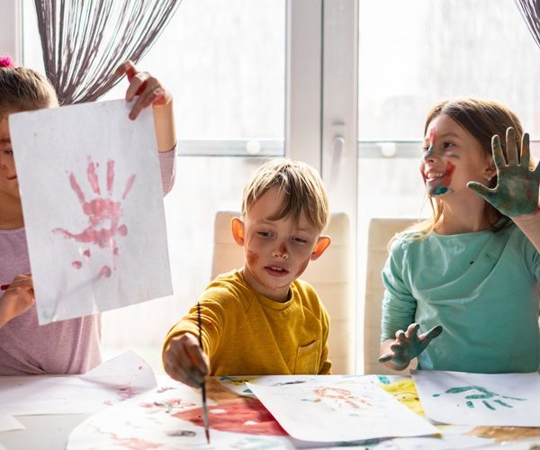 Kreativitaet foerdern: drei Kinder basteln und malen