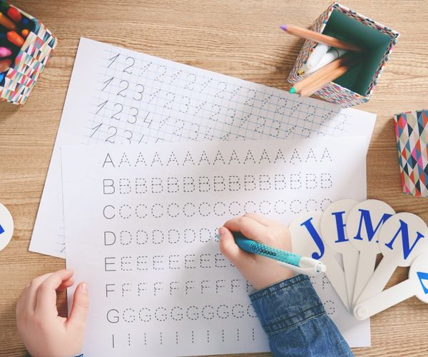 Buchstaben schreiben lernen: Kind mit Uebungsblatt