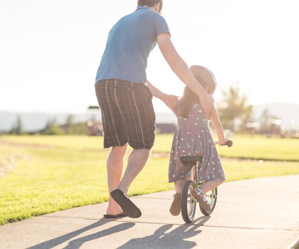 Fahrrad fahren lernen: Kind mit Vater beim ueben