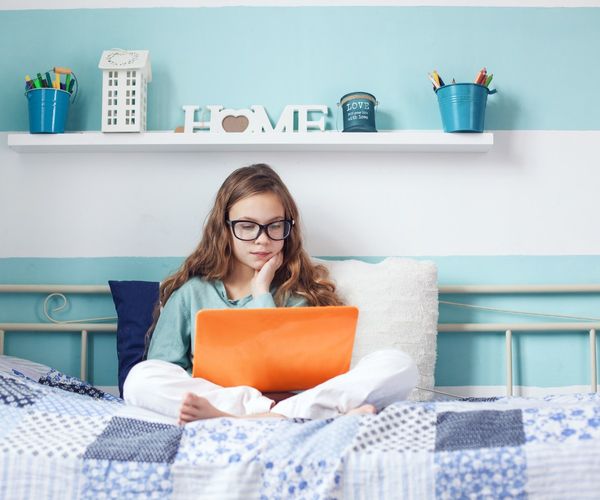 Nachhilfe Essen: Schuelerin mit Laptop auf Bett