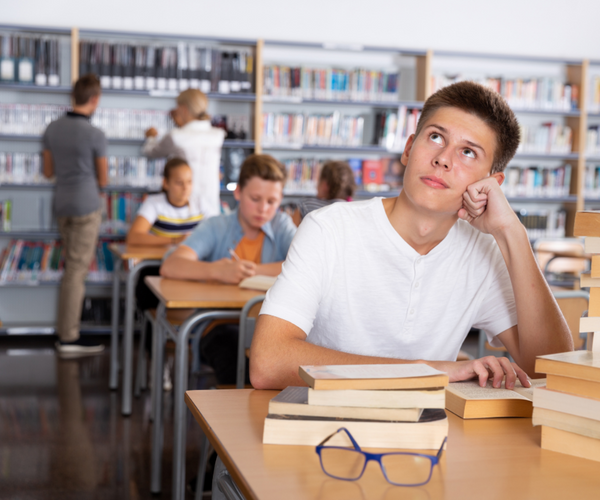 Schulwechsel-Realschule-Gymnasium--Junge-sitzt-am-Tisch-mit-B-chern-und-denkt-nach